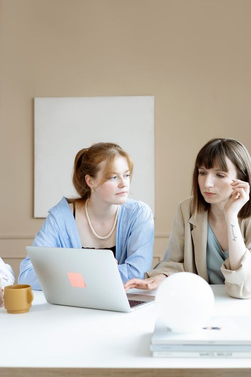 Free Two businesswomen collaborating on a project in a modern office space, focused on a laptop. Stock Photo