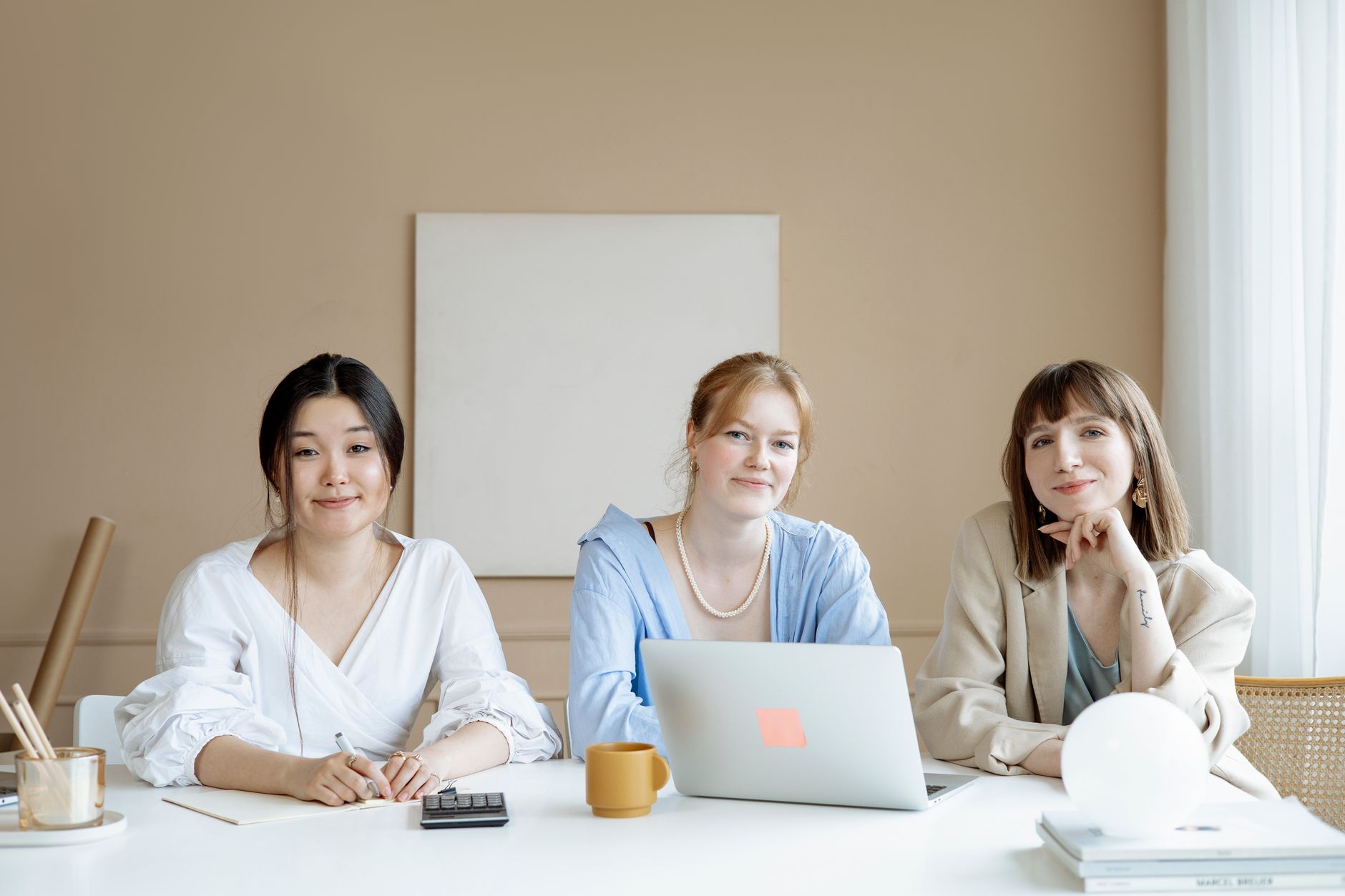 Three colleagues working together around a laptop in a bright office