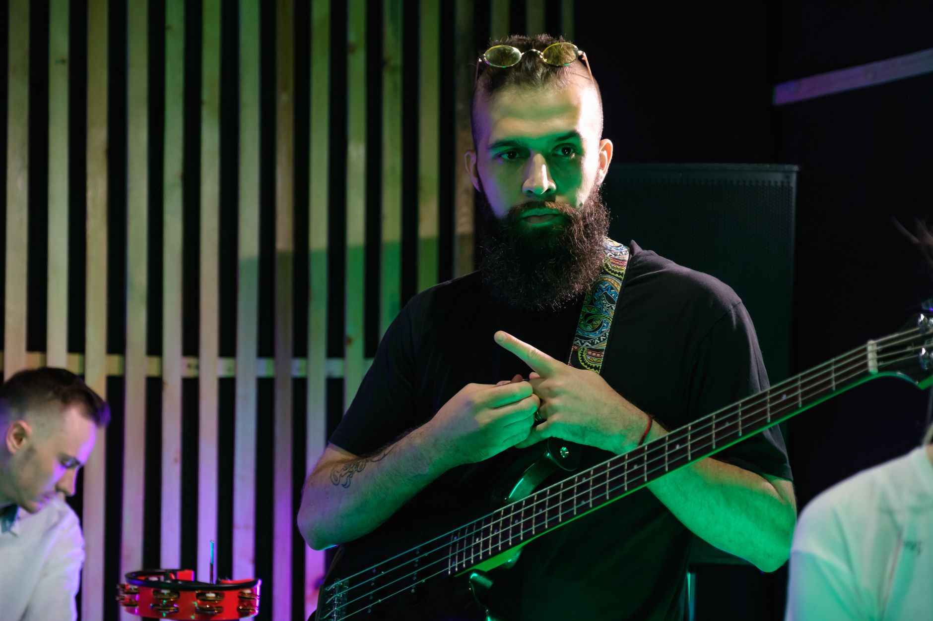 A bearded musician with a bass guitar in a modern studio environment.