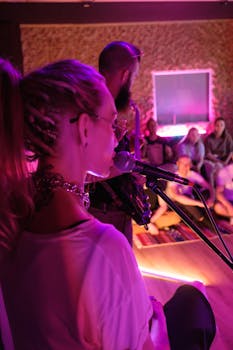 A close-up of a female singer performing live with an audience in a cozy indoor setting.