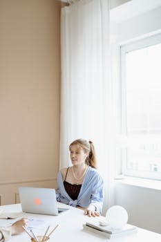 Businesswoman working on laptop in modern office with natural light.