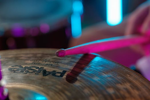 Dramatic close-up of a drumstick striking a cymbal capturing the essence of live music performance.