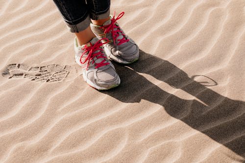 Close-Up Photo of Gray and Pink Sneakers on the Sand