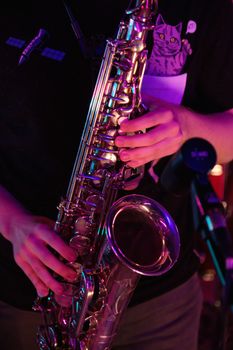 Detailed view of a saxophone being played with vibrant lighting, jazz music ambiance.