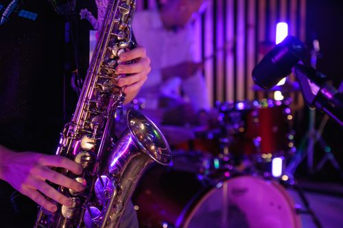 Free Musicians playing saxophone and drums during a vibrant live performance. Stock Photo