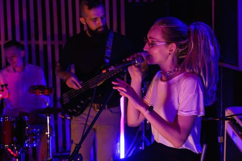 Free A vibrant live performance by an indie band with a female vocalist in an intimate setting. Stock Photo