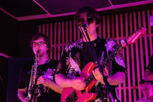 Live band performance featuring guitar, vocals, and saxophone under vibrant stage lighting.