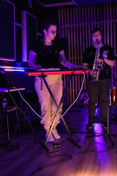 Musicians performing live with keyboard and saxophone in a neon-lit studio, creating an immersive music experience.