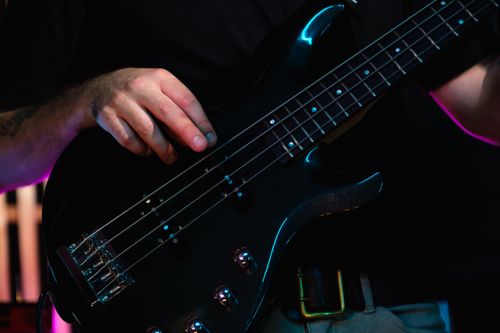 Free Close-up of hands playing a bass guitar, highlighting finger placement and string detail. Stock Photo