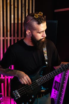 Bearded musician rehearsing in a music studio with electric guitar and vibrant lighting.