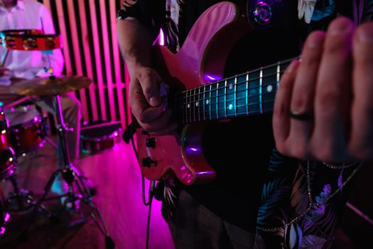 Close-up of hands playing electric guitar during a live band performance.