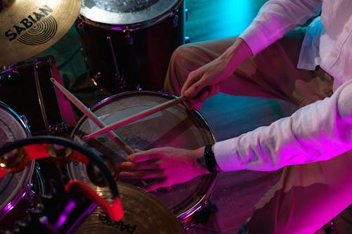 Person in Pink Long Sleeve Shirt Playing Drum