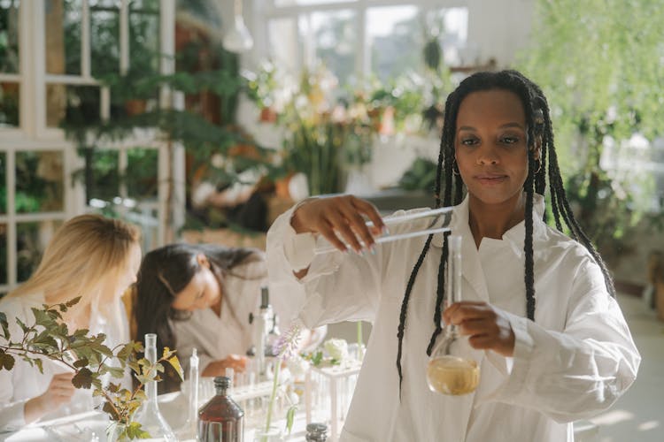 Woman In White Lab Gown Holding Clear Glass Cylinder