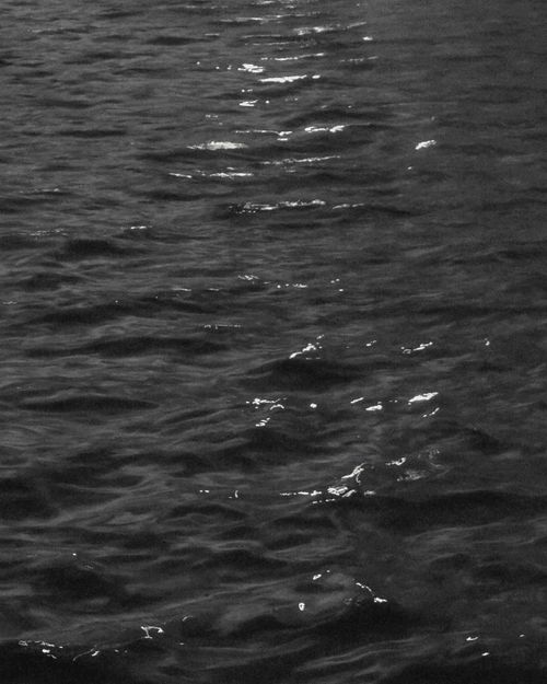 Free A tranquil monochrome ocean surface with reflective ripples under natural light. Stock Photo