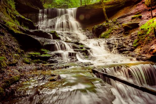Free A serene waterfall cascades through a lush, vibrant forest setting. Stock Photo