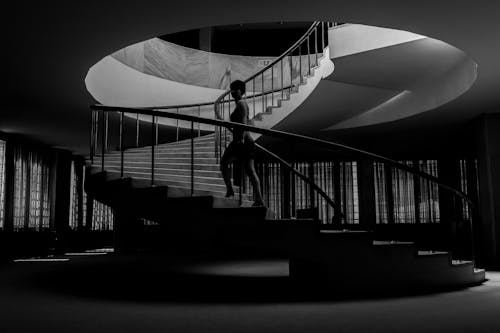 Grayscale Photo of a Woman Going Upstairs