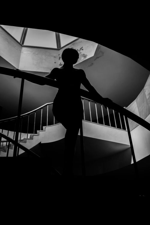 Free A dramatic black and white image of a woman's silhouette on a spiral staircase. Stock Photo