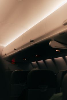 Moody shot of an airplane cabin's interior, focusing on the overhead bins in dim lighting.