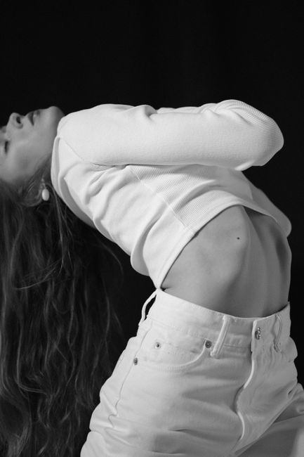 Graceful black and white portrait of a woman exhibiting flexibility and elegance through a bending pose.