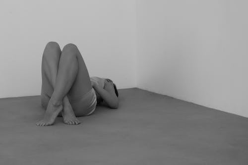 A Grayscale Photo of a Woman Lying Down on the Floor