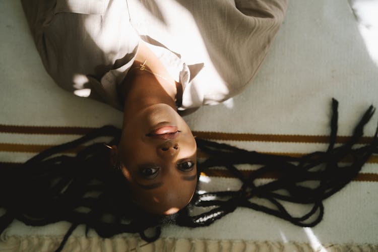 Woman In Afro Braids Lying While Looking At The Camera