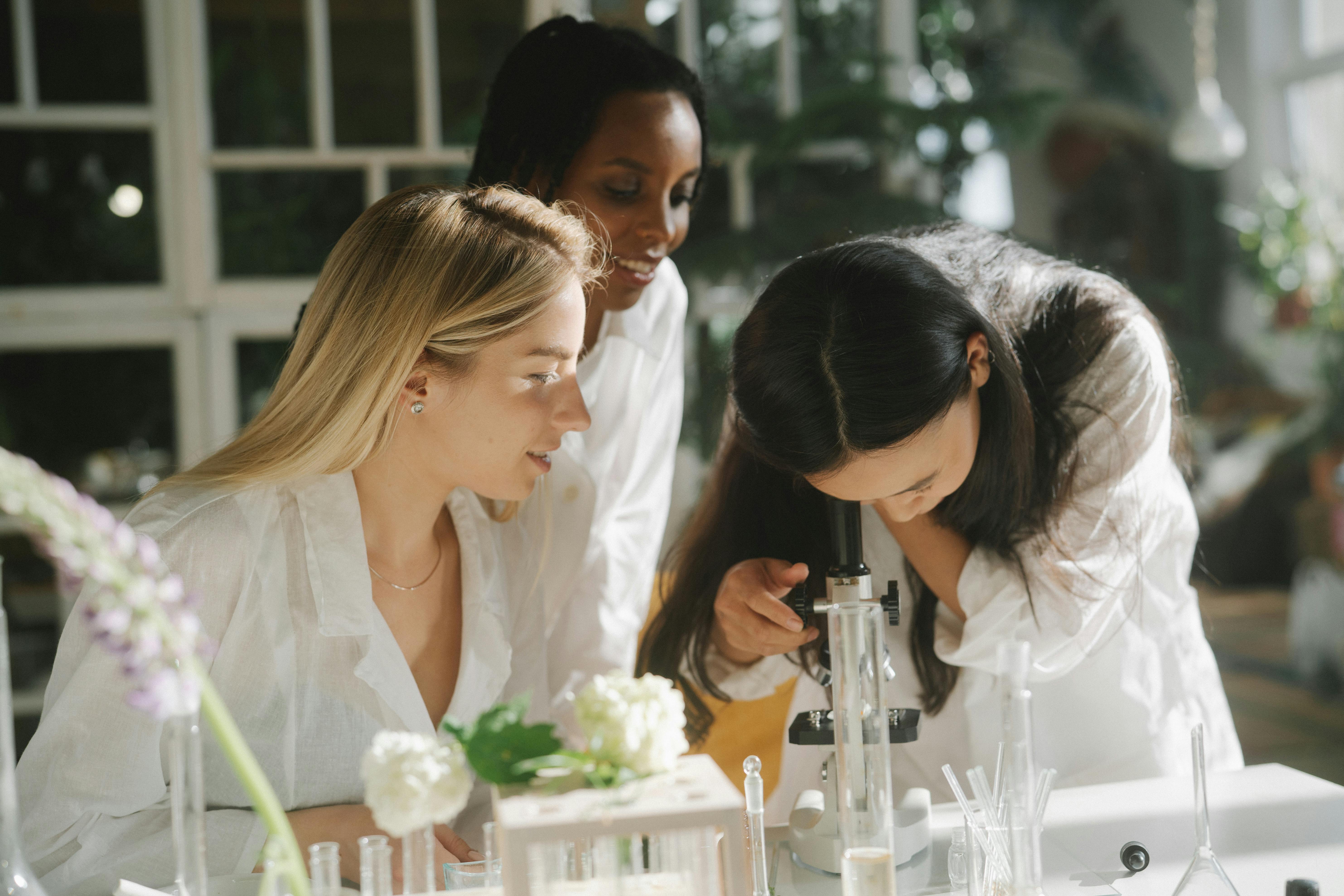 Three young women scientists working together in a bright laboratory setting.