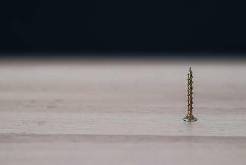 Close-up Photography of a Brass Colored Screw on Top of the Table
