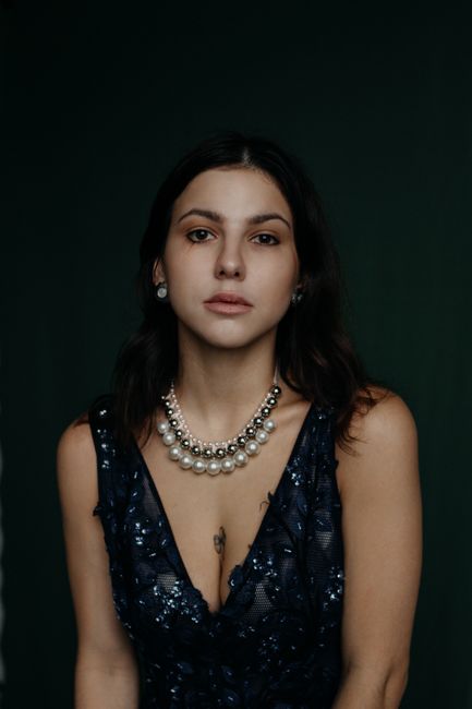 Portrait of an elegant woman wearing a beaded dress and pearl necklace indoors.