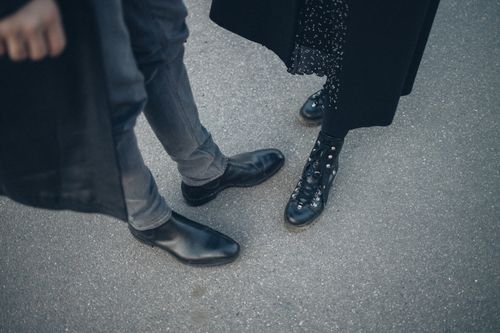 Free A fashionable couple shows off their black leather footwear while standing together on a city street. Stock Photo