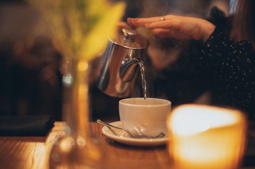 Free Person pours hot water in a cozy cafe, creating a calm and inviting atmosphere. Stock Photo