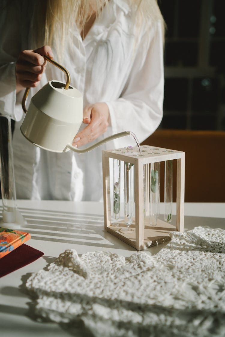 A Person In White Long Sleeves Pouring Water On Test Tubes On The Rack