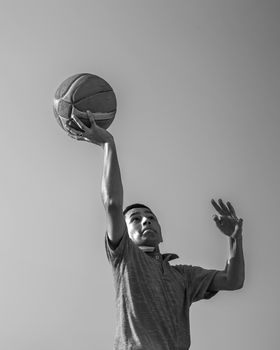 Dynamic grayscale shot capturing a basketball player in mid-air dunking motion against a plain background.