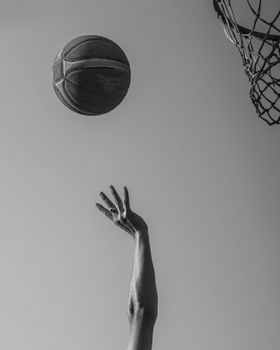 A monochrome image capturing a basketball in mid-air approaching the hoop.