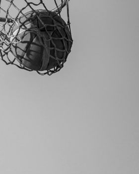 A black and white image of a basketball swishing through the hoop.