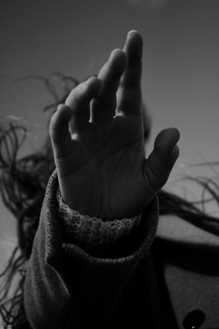 Artistic monochrome image of a raised hand in a knitted sweater, creating mystery.
