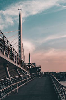 A modern cable-stayed bridge with people walking during twilight, showcasing urban architecture.