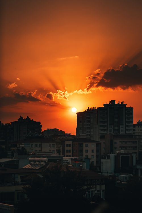 Free A stunning sunset casting vibrant orange hues over a city skyline, creating a dramatic silhouette. Stock Photo