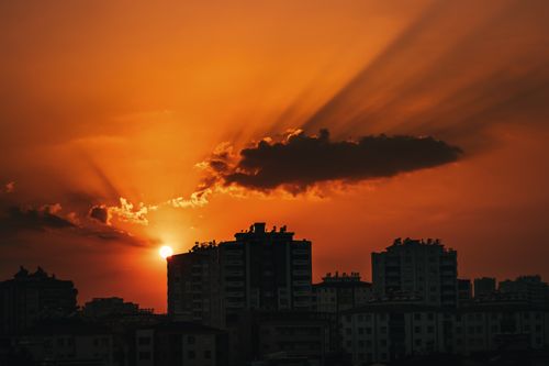 Free Dramatic sunset over a city skyline with silhouette skyscrapers and vivid orange sky, capturing urban serenity. Stock Photo