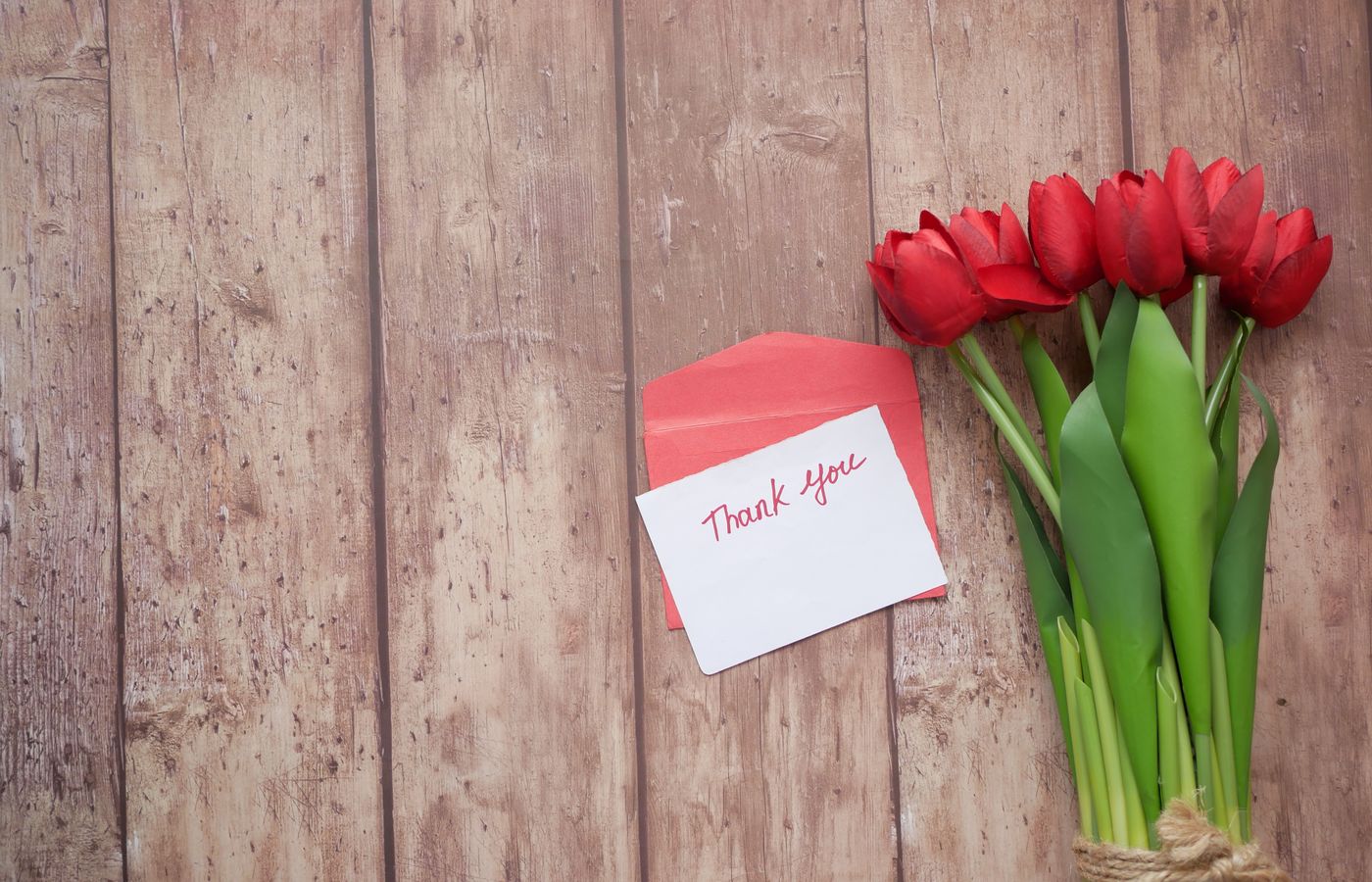 A charming rustic-themed thank you note with red tulips on a wooden background.