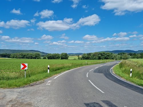 Free A winding road through lush countryside under a clear blue sky, ideal for travel concepts. Stock Photo