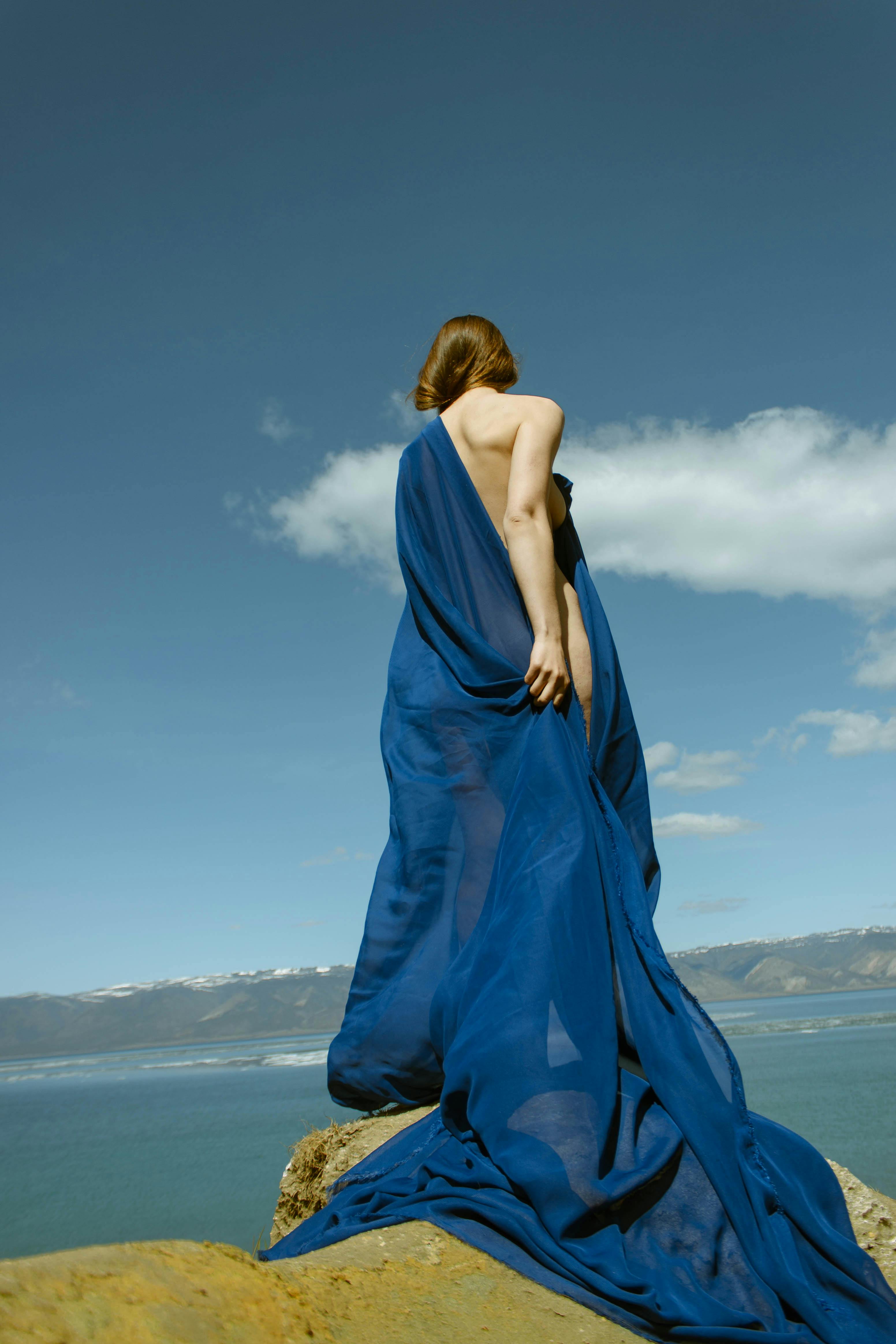 naked woman with blue fabric draped over her shoulders