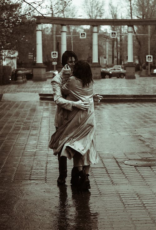Free Black and White Photo of a Man Holding a Woman Under the Rain Stock Photo