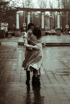 A couple in love dances passionately in a rainy city street.