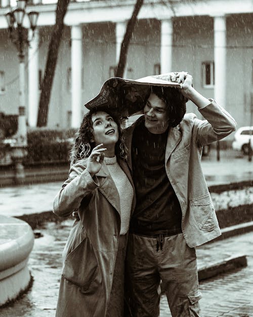Free Grayscale Photo of Couple Covering their Heads from Rain Stock Photo