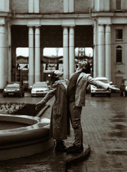 A romantic scene of a couple enjoying the rain in a sepia-toned urban setting.