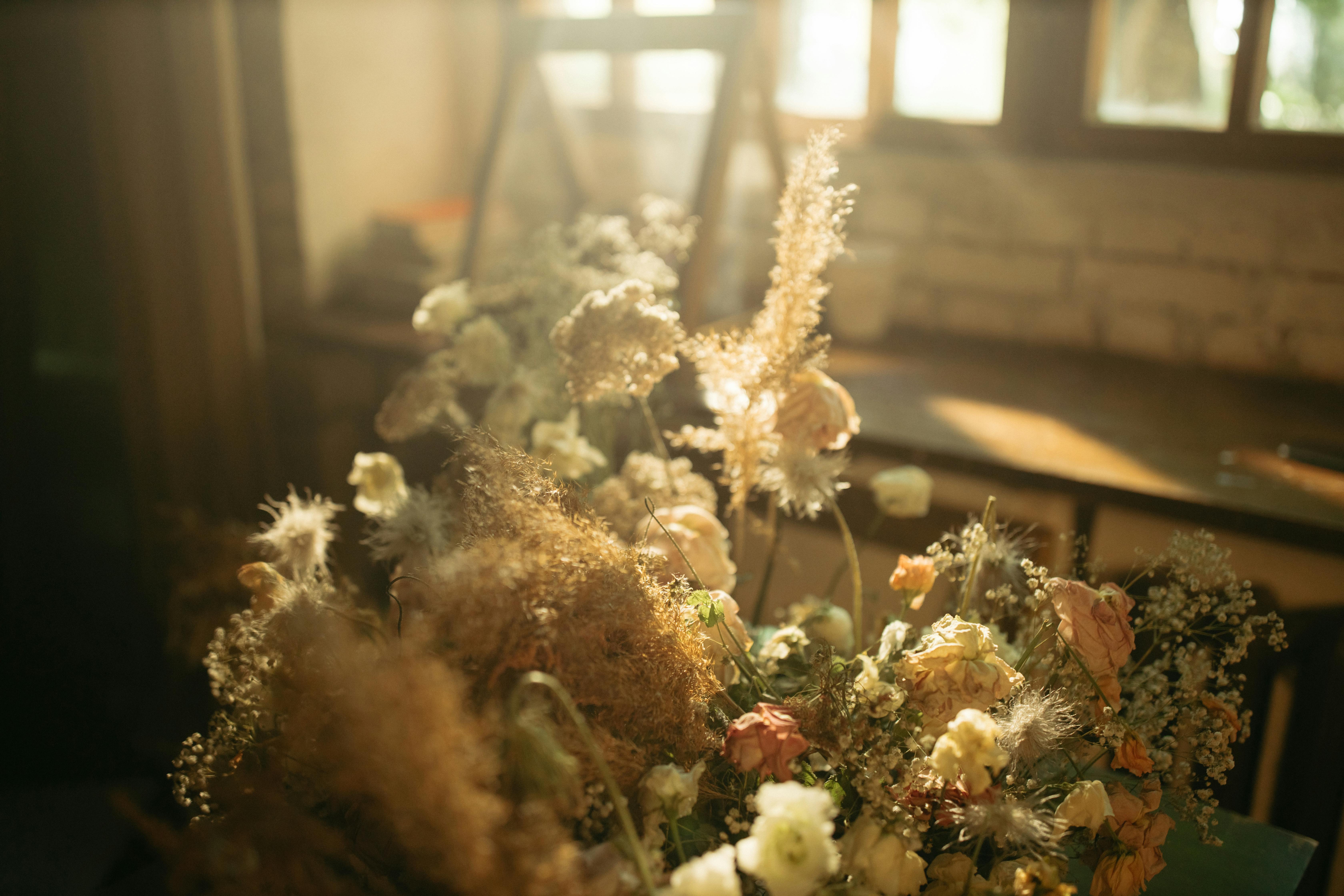 A warm, sunlit dried floral arrangement near a rustic window, capturing natural light indoors.