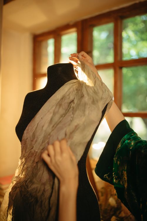 Free Hands gracefully draping fabric over a dress form in a sunlit studio, capturing the art of tailored fashion. Stock Photo