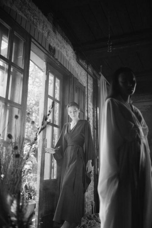 Free Two women in elegant dresses pose in a grayscale indoor scene, exuding fashion and style. Stock Photo
