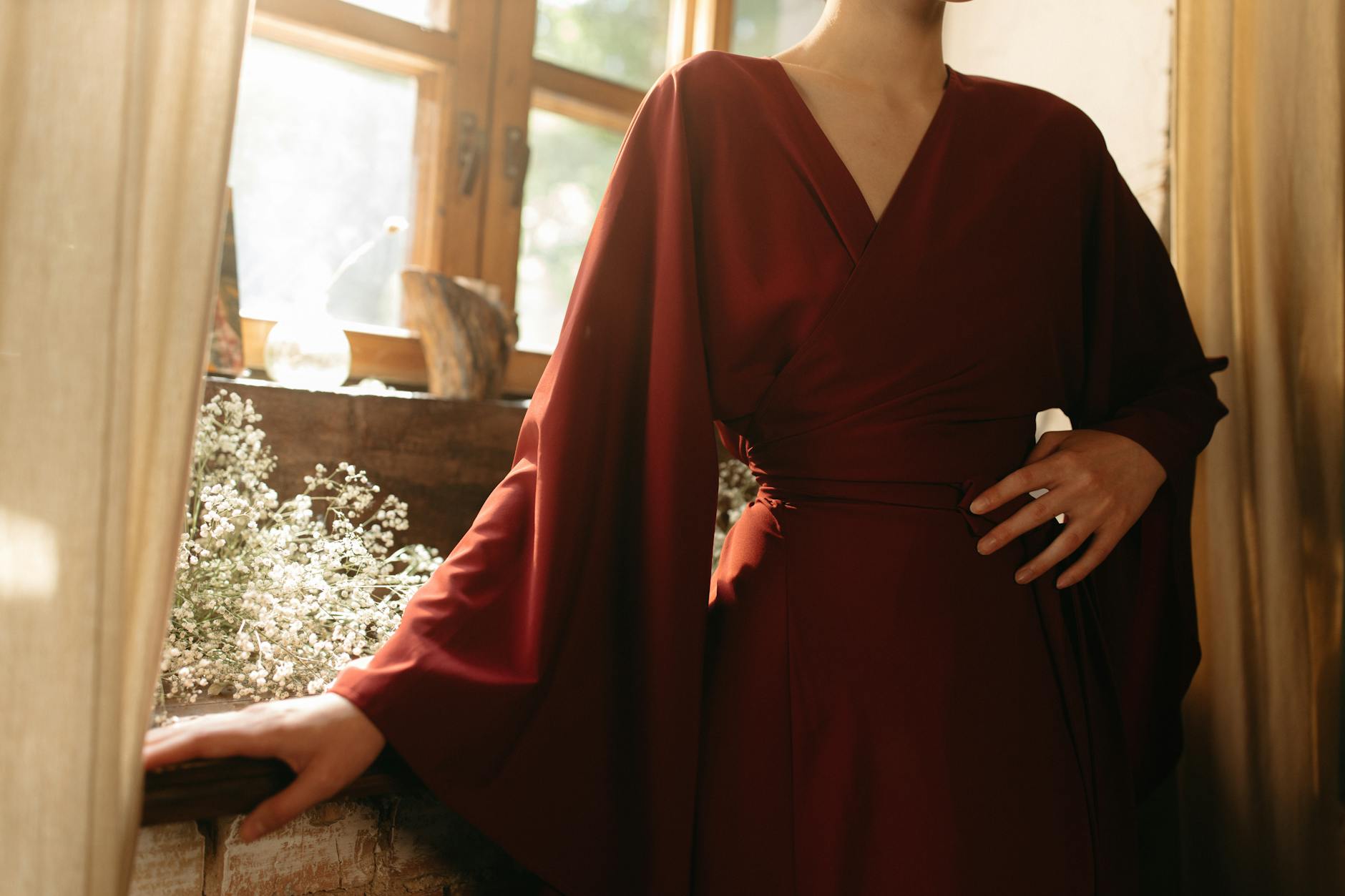 Woman in Red Robe Standing Near Window