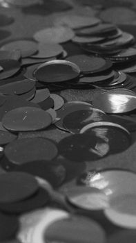 Monochrome photo of circular confetti scattered on a surface, creating a textured pattern.